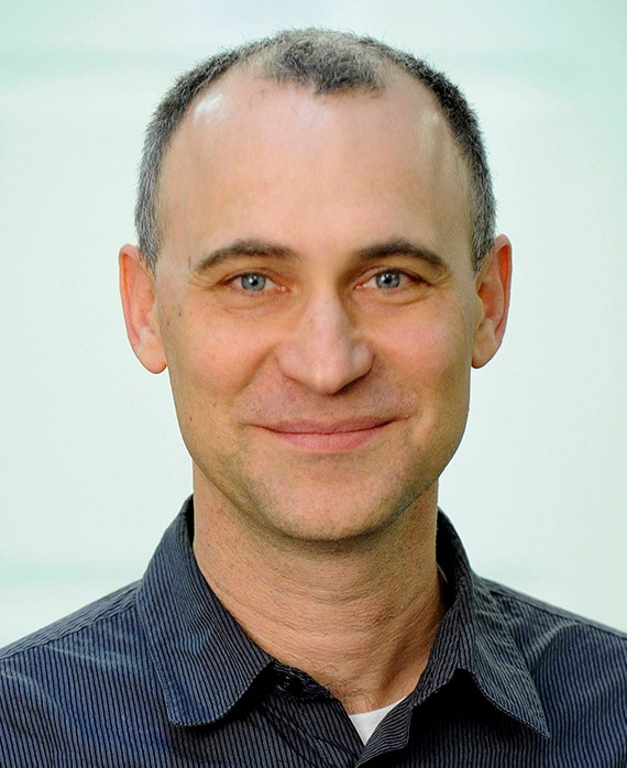 Joel Fields headshot wearing a navy striped collar shirt
