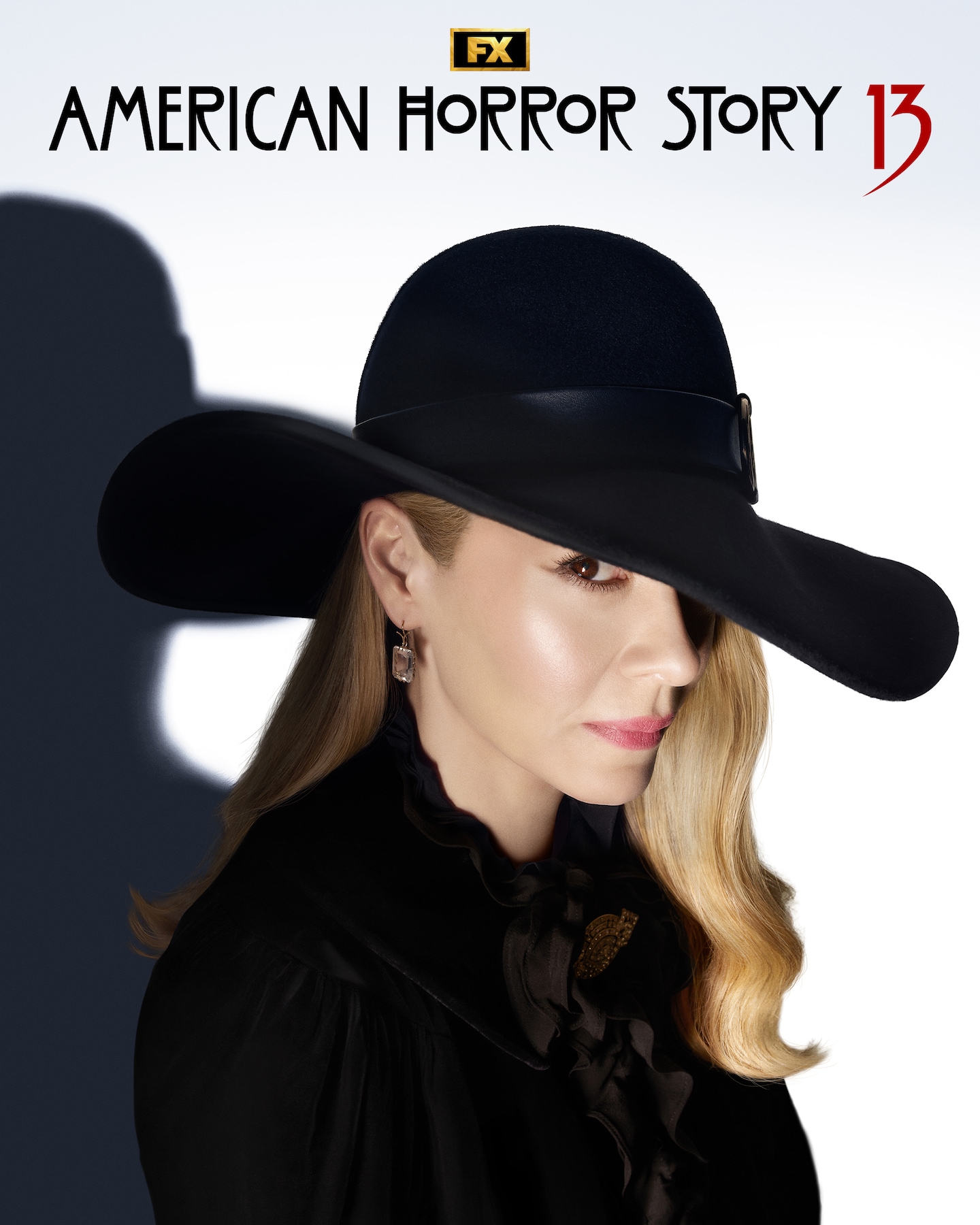Sarah Paulson wearing a black hat, black coat, and diamond earrings.