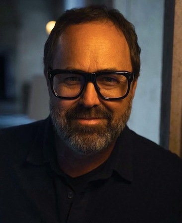 Scott Robertson headshot wearing a black button up shirt and black glasses