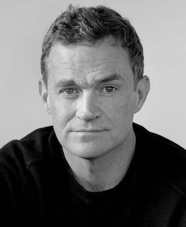 Black and white headshot of Patrick Radden Keefe in a black shirt.