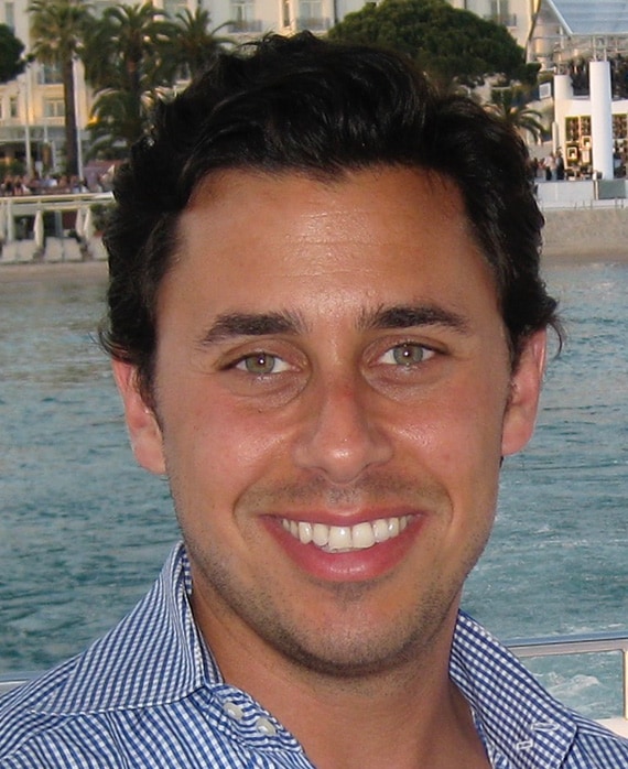 Headshot of executive producer of FX's Necaxa, Nicholas Frenkel, wearing a checkered button up at the beach.