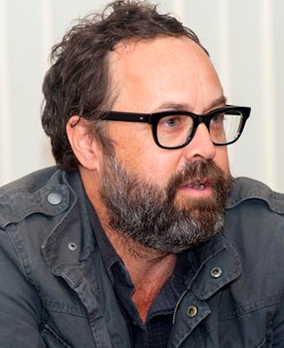 Headshot of Scott Robertson, Executive Producer of FX's Grotesquerie, in grey jacket and black glasses.