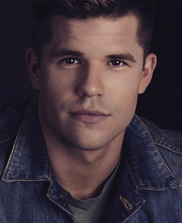 Charlie Carver headshot wearing a jean jacket and grey shirt