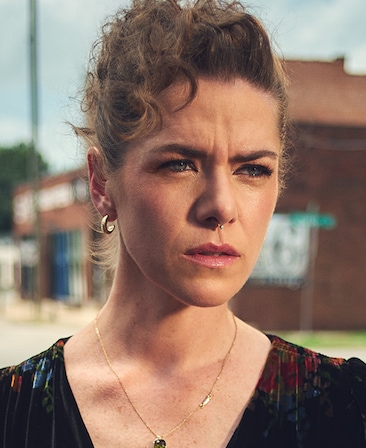 Headshot of Kaniehtiio Horn as Samantha in FX's The Lowdown, wearing a multicolored velvet dress and gold jewelry.