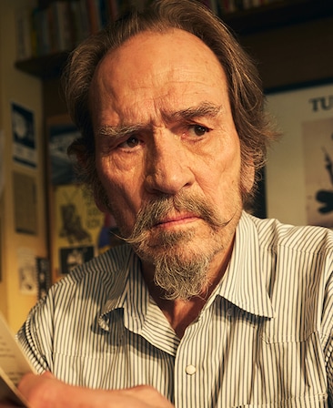 Headshot of Tommy Lee Jones as Lee Raybon Senior in FX's The Lodown wearing a striped button up holding a book.