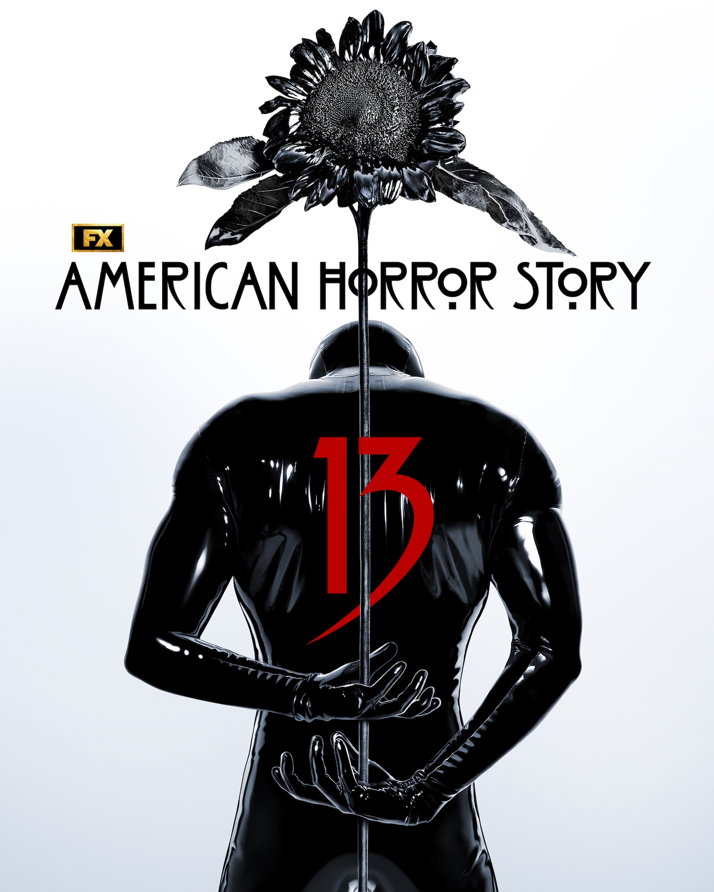 Man wearing a black leather suit with a "13" on the back, holding a dead black sunflower behind his back.