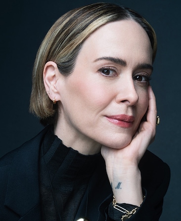 Sarah Paulson headshot wearing a black top with gold metal detailing for AHS: 13