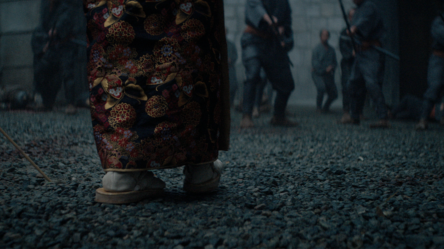 Close up of Mariko's sandaled feet walking through the castle ground towards Ishido's men