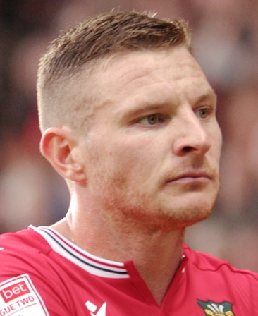 Paul Mullin headshot wearing a red shirt with a striped collar