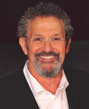 Headshot of executive producer Thomas Schlamme wearing a suit and silver glasses.