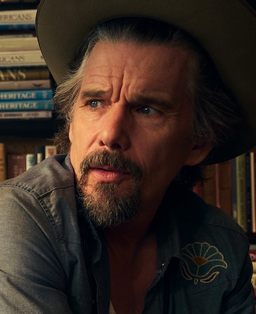 Headshot of Ethan Hawke as Lee Raybon in FX's The Lowdown, wearing a denim decorated long sleeve with a grey fedora.