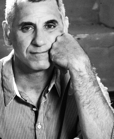 David Zuckerman headshot placing his hand on his face and wearing a striped button up
