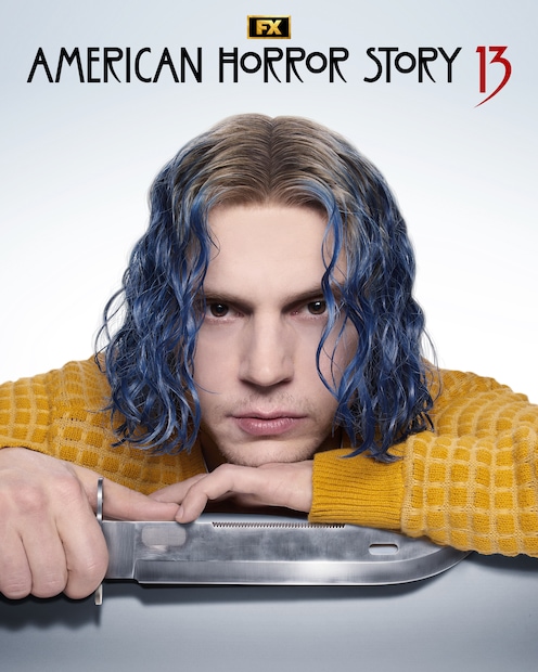 Evan Peters with blue hair and a yellow sweater holding a knife.