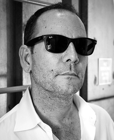 Tim Minear headshot wearing a white button up shirt and black glasses