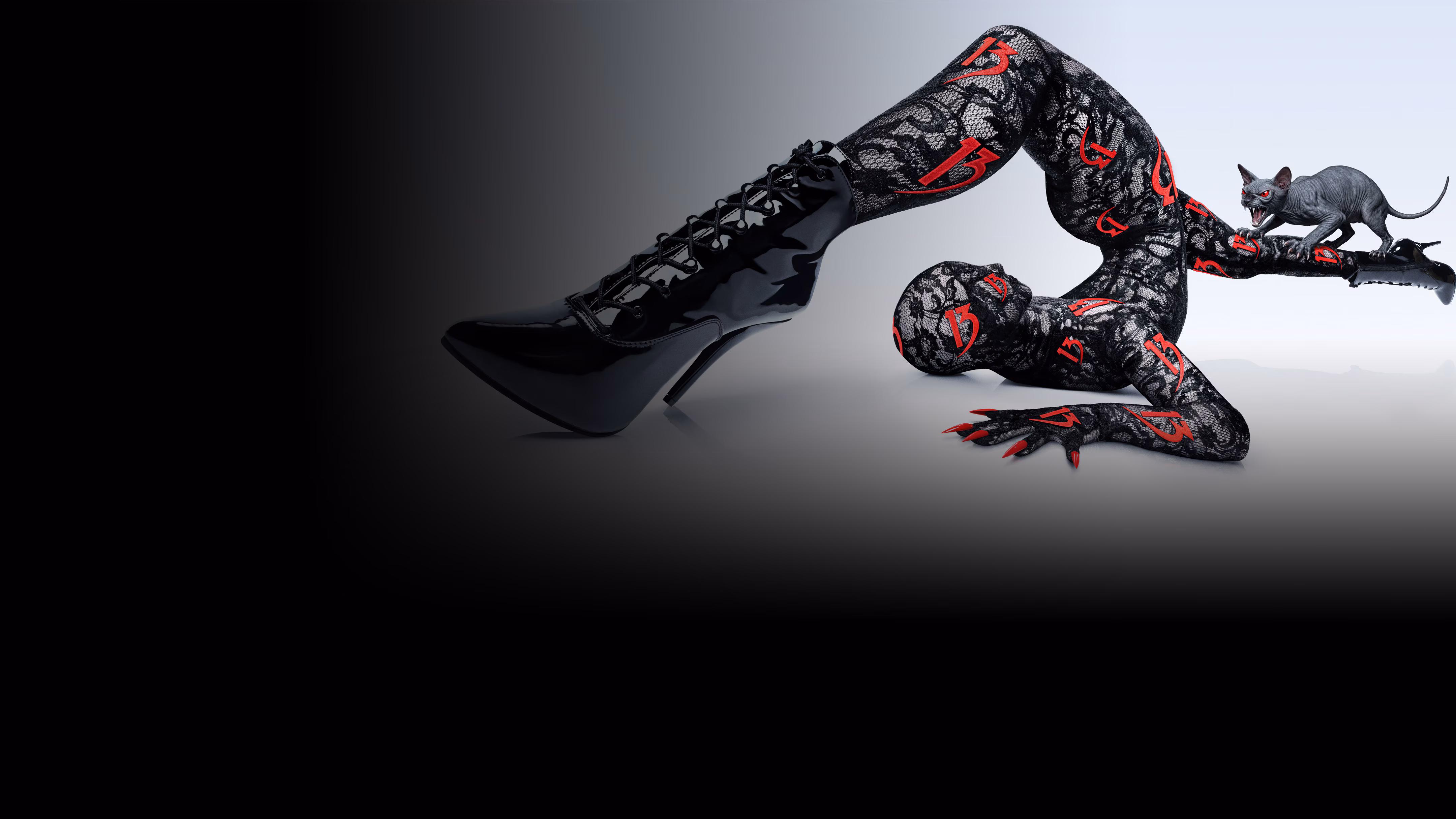 Contortionist posing wearing a lace bodysuit with "13" throughout it, a sphinx cat with red eyes is screeching on her leg.
