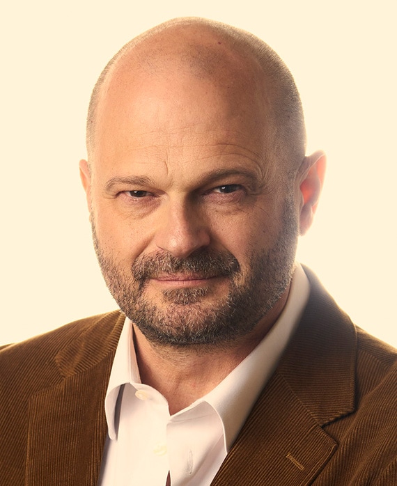 Brad Simpson headshot white button down with a brown corduroy suits