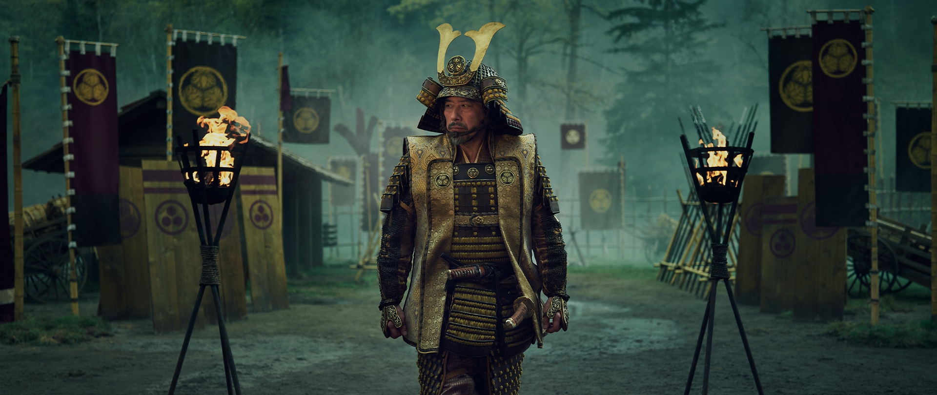 Lord Toranaga in full busho armor standing in front of his war camp amid torchlights