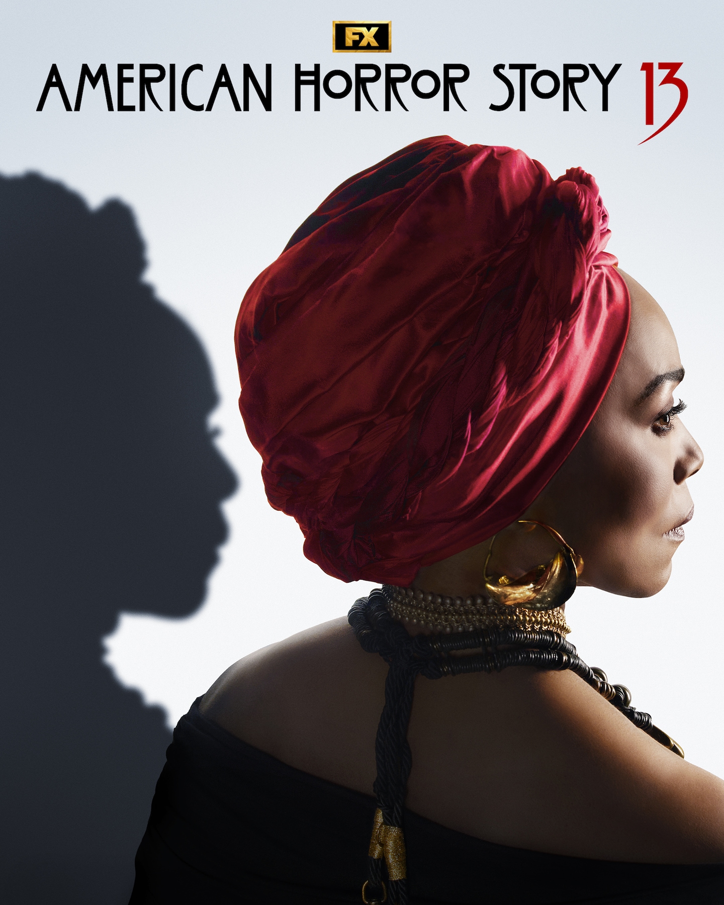 Angela Basset wearing a red head scarf and gold jewelry looking away.