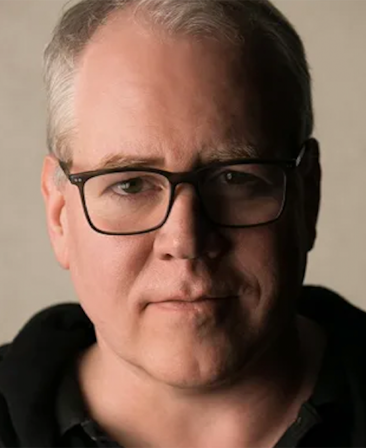 Headshot of FX's The Shards executive producer Bret Ellis wearing a black hoodie and black glasses.