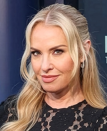 Leslie Grossman headshot wearing a black lace top and sparkly earrings.