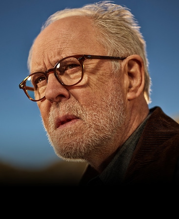 John Lithgow headshot wearing a brown jacket