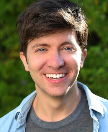 Seth Kirschner headshot wearing a gray shirt and blue collar shirt standing outside