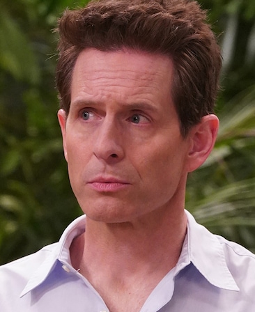 Glenn Howerton headshot wearing a light blue button up outdoors with trees behind him.